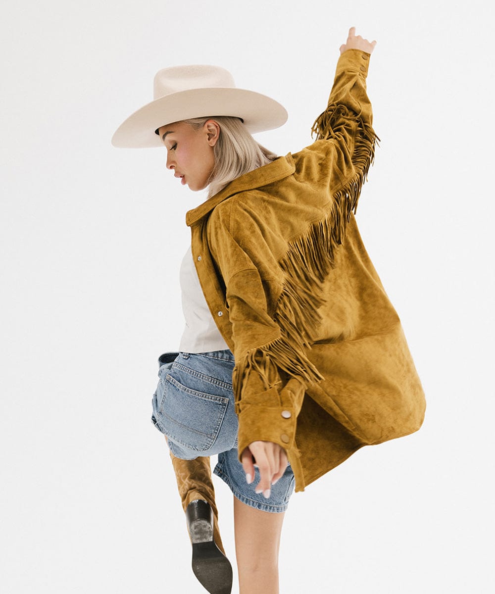 Fashion model in a Lane Cowboy Hat and fringed mustard jacket, showcasing bold Western style.