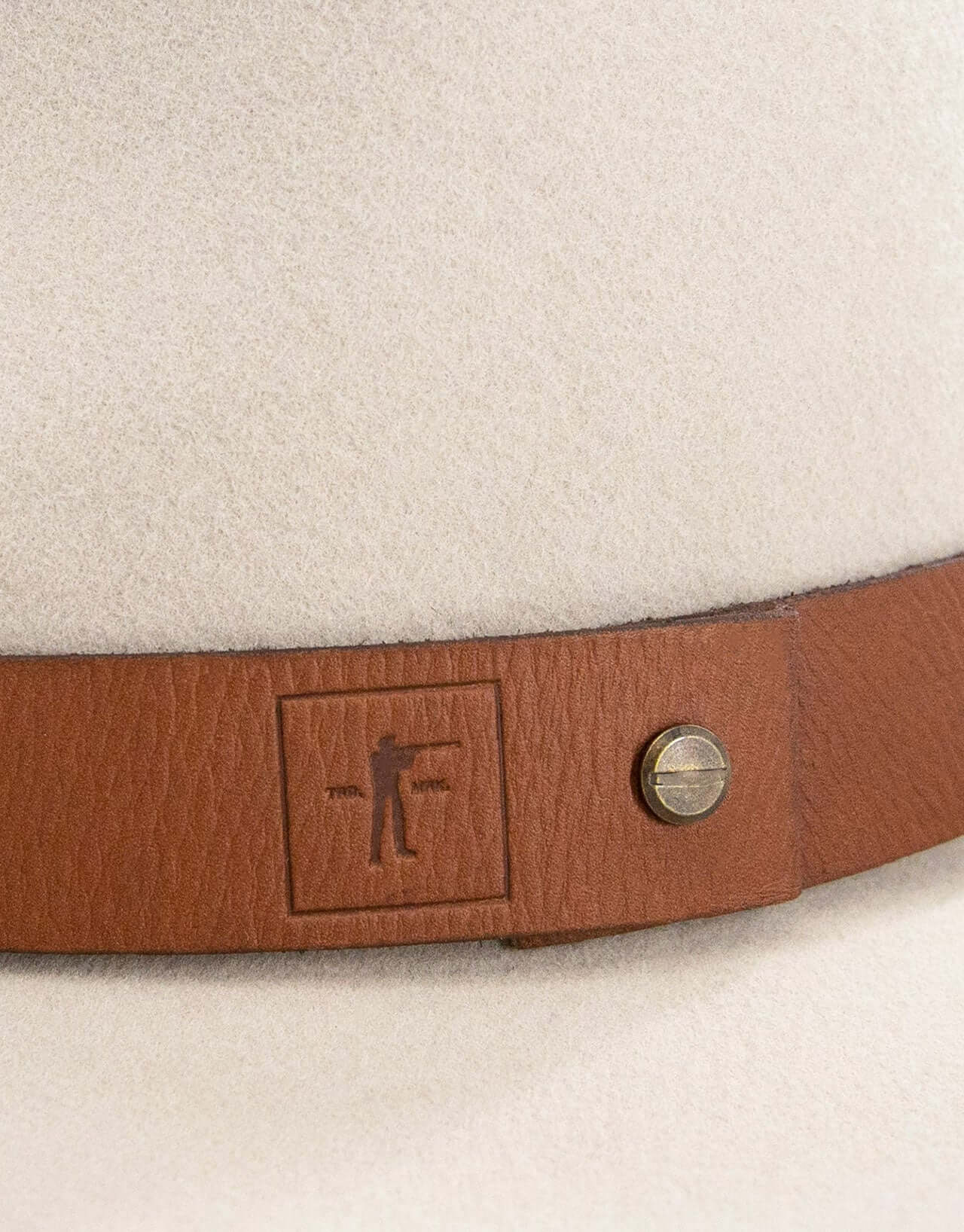 Close-up of the leather band on a Brimmed Field Hat featuring an antique brass screw and logo.