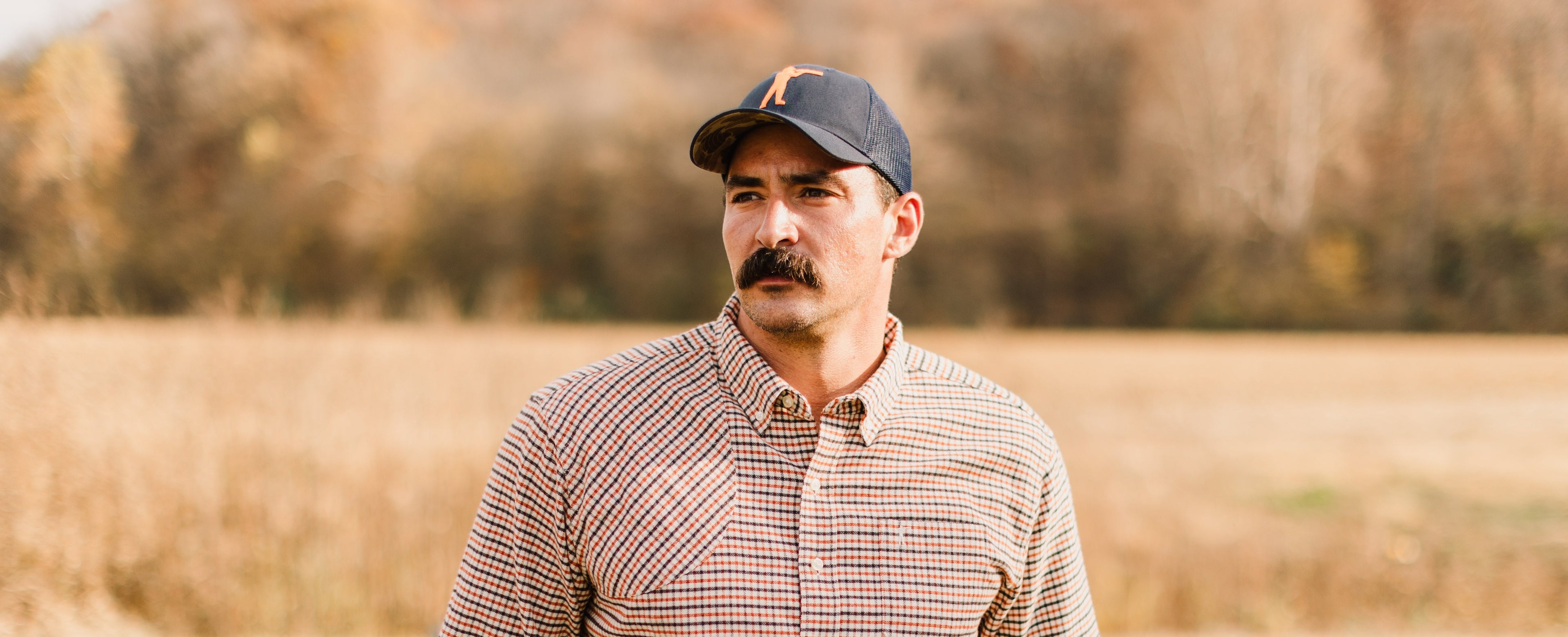 Man wearing an Arthur Core Snapback Hat in a natural outdoor setting, showcasing style and comfort.