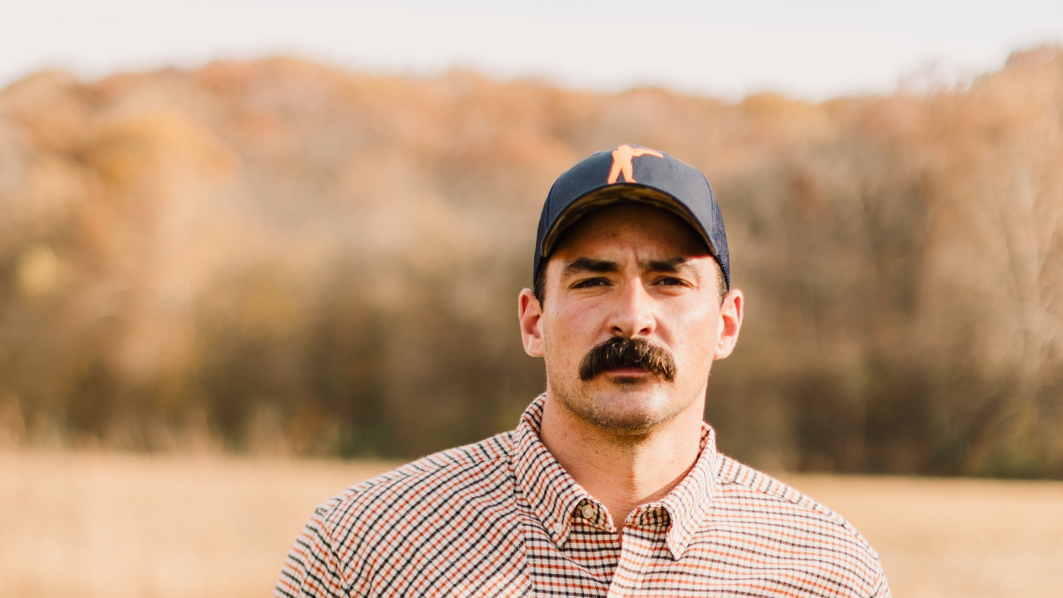 Man wearing Arthur Core Snapback Hat in a scenic autumn setting, showcasing a stylish outdoor look.
