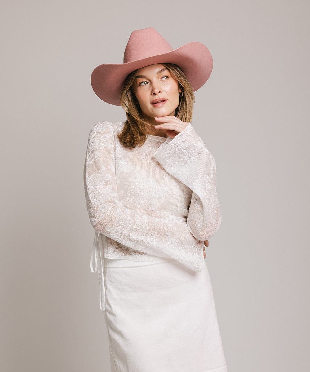 Woman wearing a pink Teddy Cattleman cowboy hat and a stylish lace blouse, perfect for country-inspired fashion.