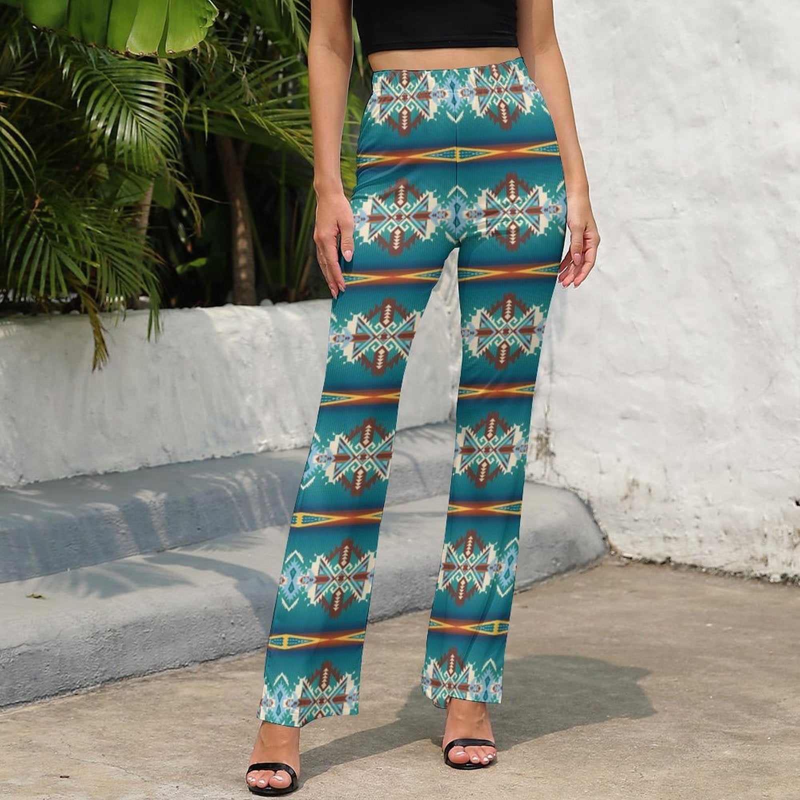 Model wearing teal Aztec flare pants with a high waist and bold southwestern print, perfect for festivals and casual outings.