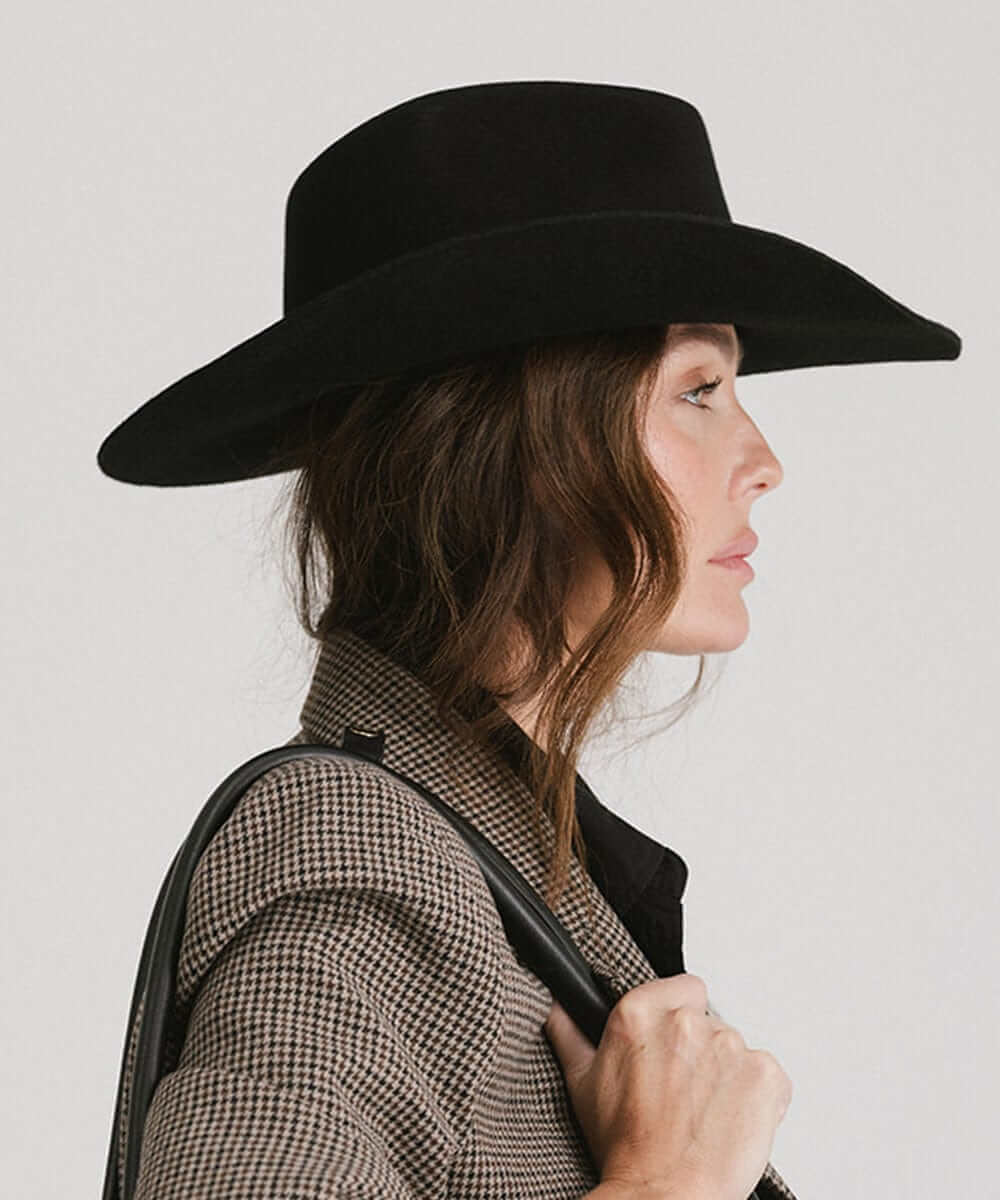 Profile view of a woman wearing a black Dean Rancher Cowboy Hat paired with a stylish blazer.