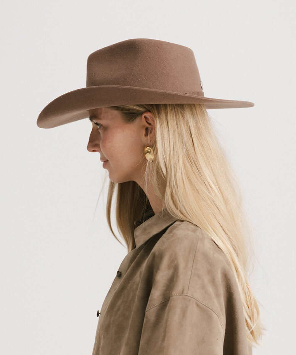 Side profile of a woman wearing a brown Dean Rancher Cowboy Hat, showcasing a sculpted crown and mid-length brim.