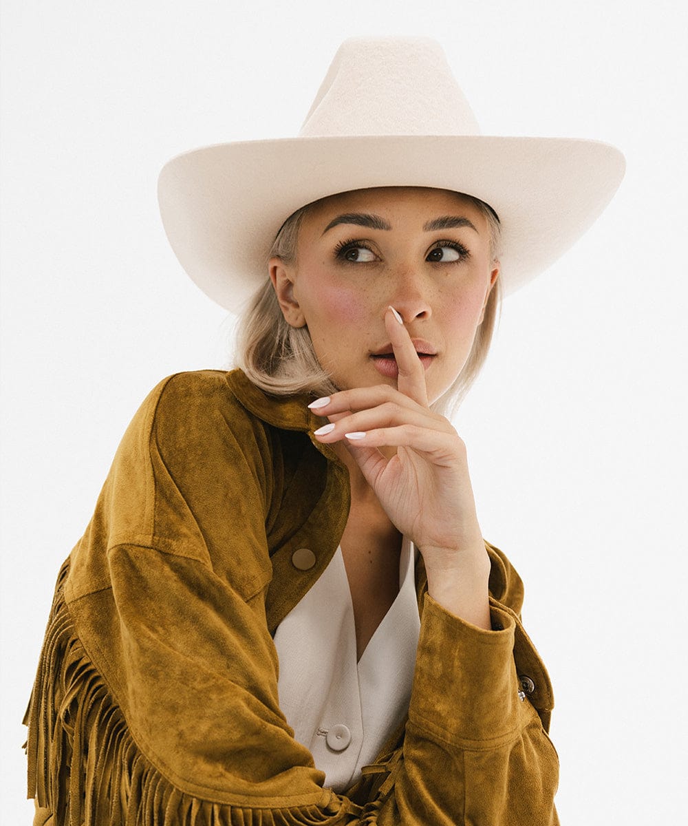 Young woman wearing a white Lane Cowboy Hat and a suede fringe jacket, creating a stylish Western look.