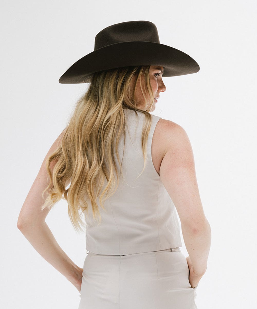 A woman in a stylish Lane Cowboy Hat, showcasing its wide brim and unique silhouette from a side view.