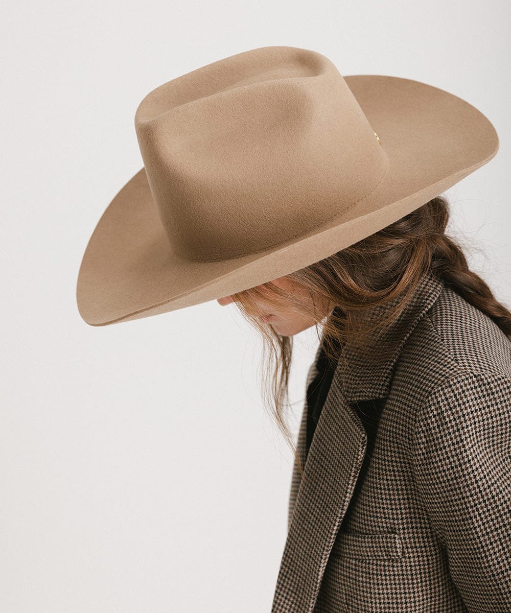 Side view of a woman wearing a beige Lane Cowboy Hat with a wide brim and stylish attire.