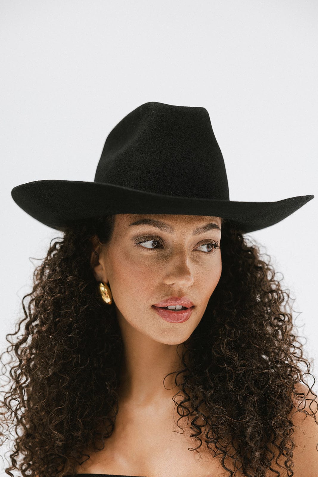 Woman wearing a stylish black Lane Cowboy Hat with a wide brim, showcasing a unique and sophisticated look.