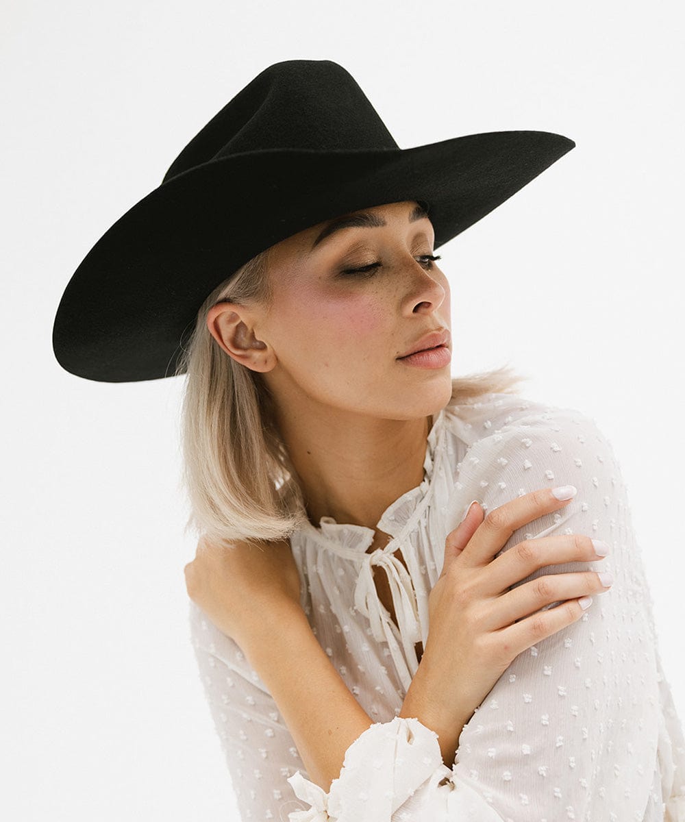 Woman wearing a black Teddy Cattleman cowboy hat, showcasing timeless western style and elegance.