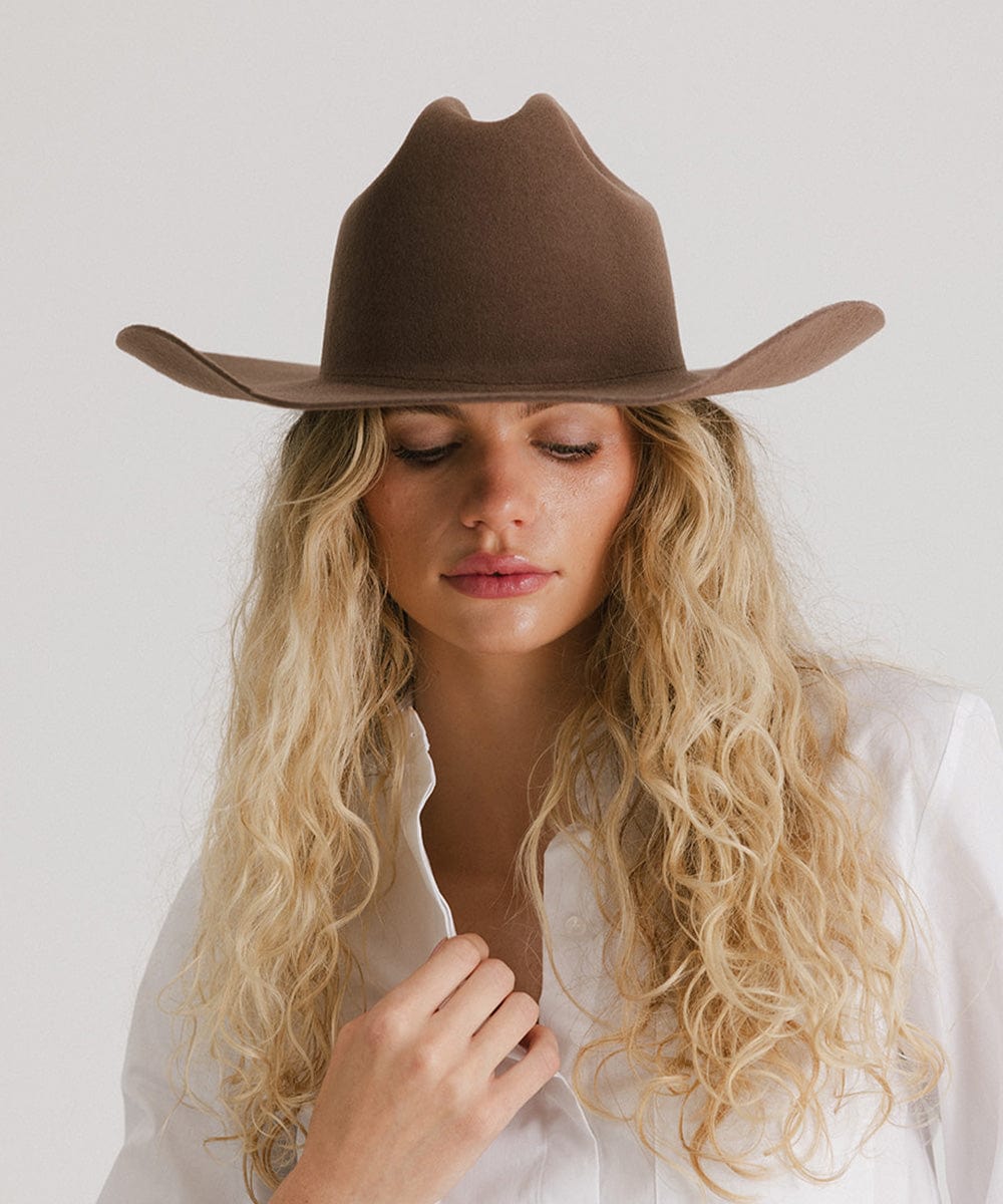 Close-up of a woman wearing a brown Teddy Cattleman cowboy hat, embodying classic western style.
