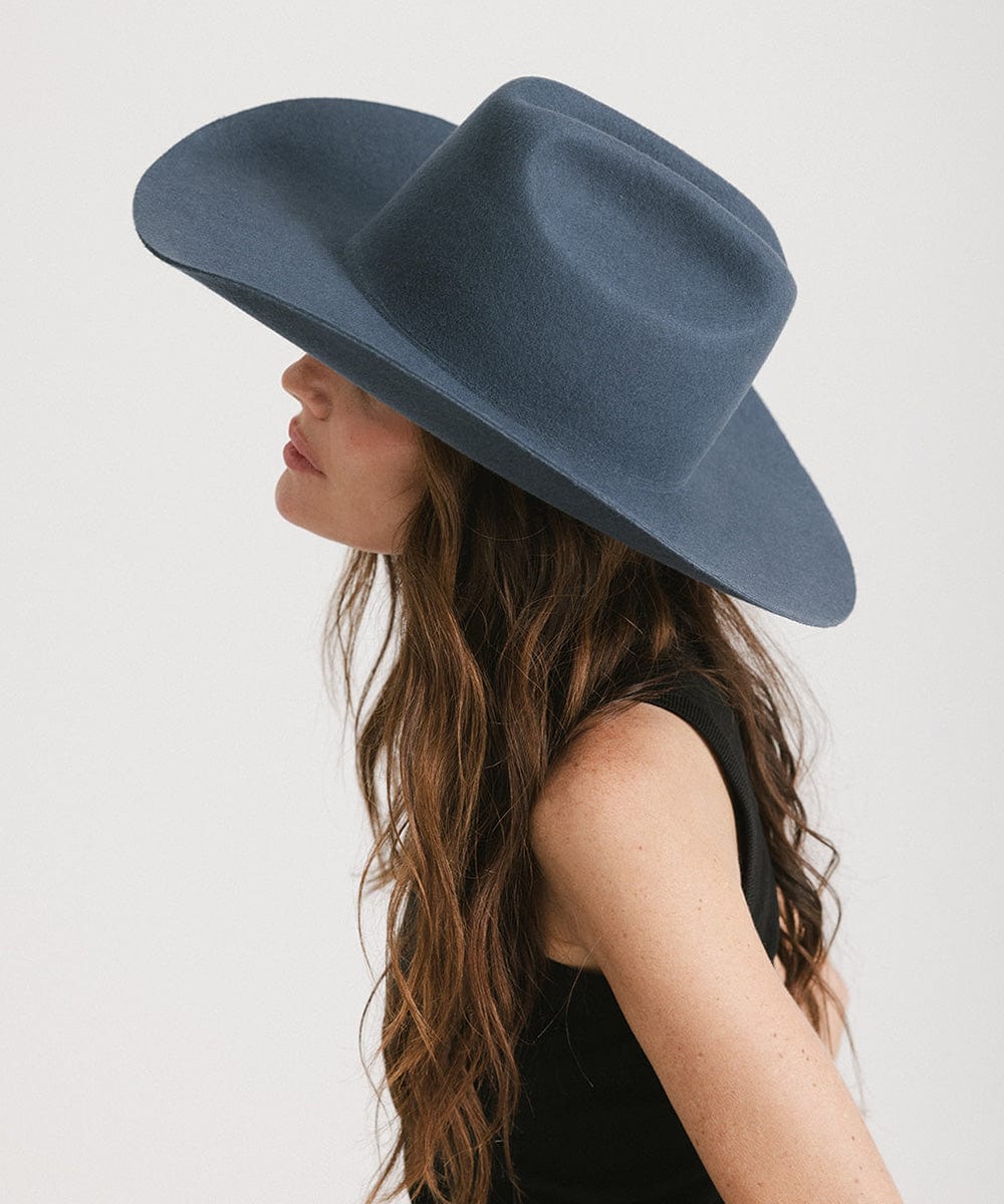 Stylish woman with long hair wearing a Teddy Cattleman Cowboy Hat in dark blue, showcasing western fashion.