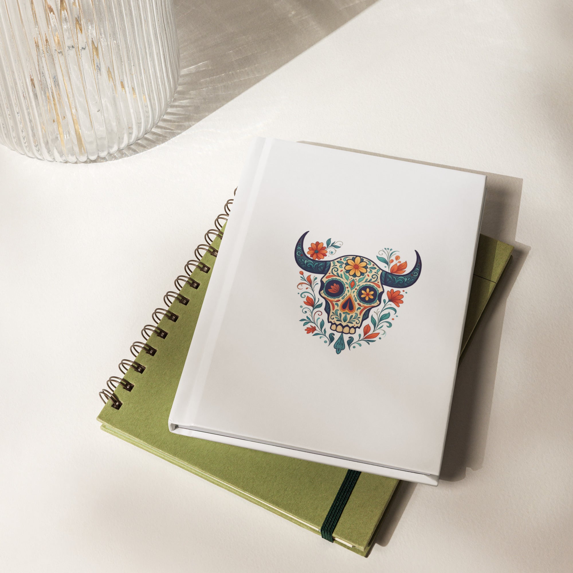 Longhorn Sugar Skull Journal with floral design on cover, resting on a green notebook, perfect for creatives.