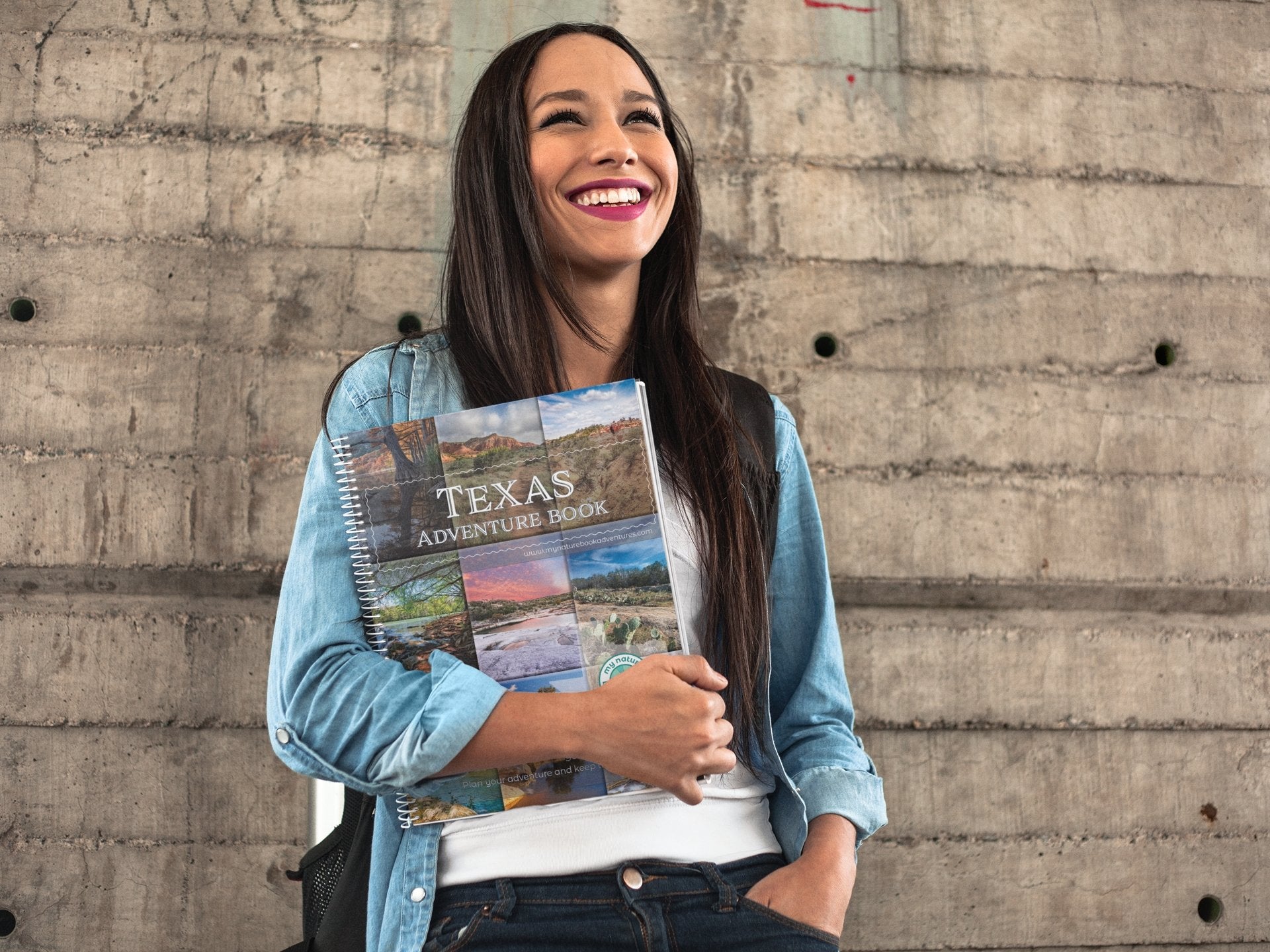 Smiling woman holding Texas Adventure Book, ready to plan her next unforgettable Texas journey.