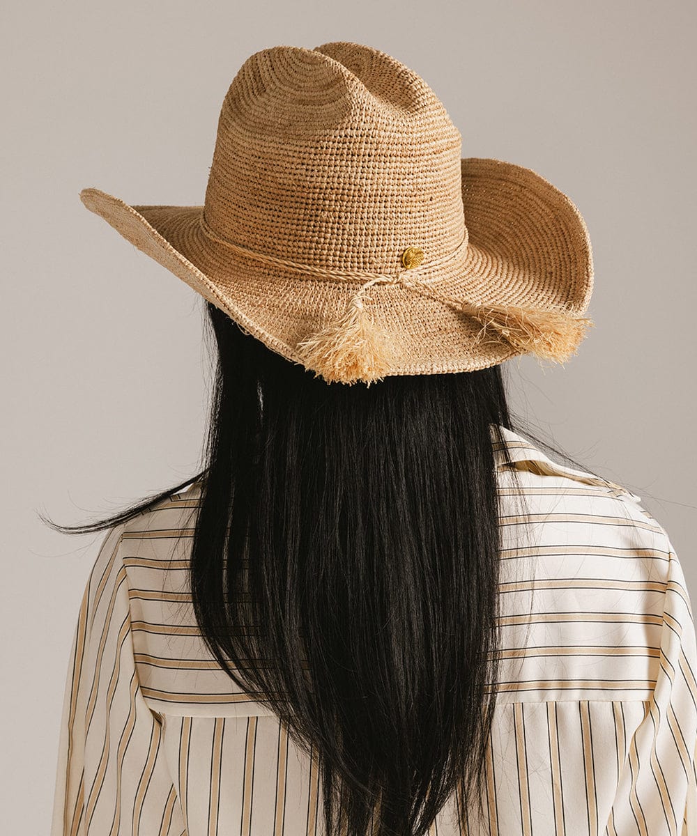 Back view of a woman wearing a lightweight Ames Packable Straw Cowboy Hat, showcasing its classic cattleman crown and braided design.
