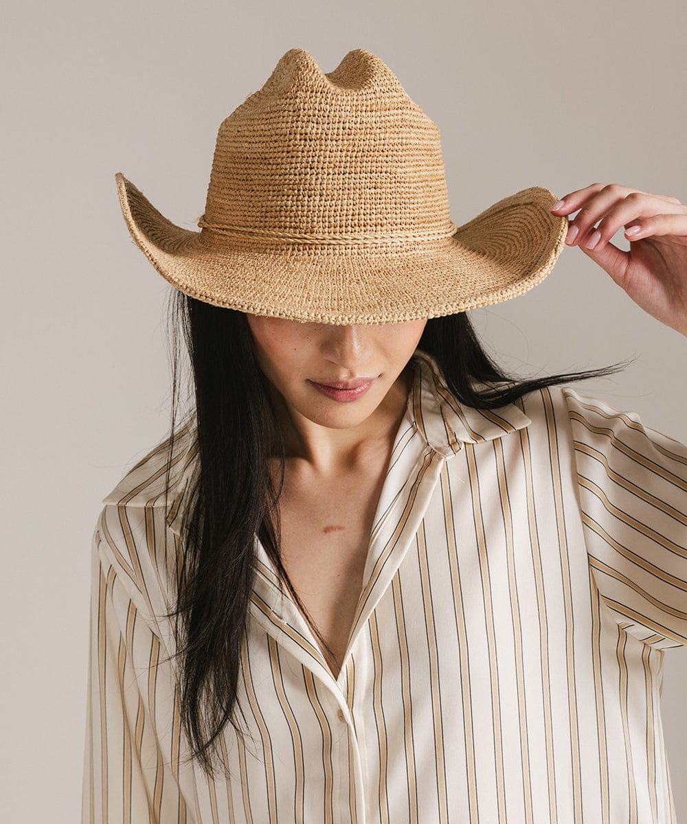 Woman wearing a packable straw cowboy hat with a classic cattleman crown, styled for a Western look.