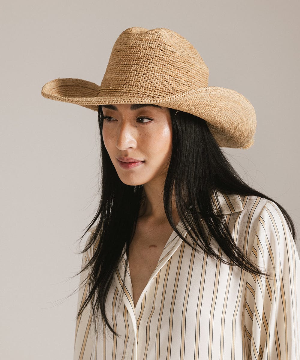 A model wearing an Ames Packable Straw Cowboy Hat, showcasing its lightweight raffia design and classic Western style.