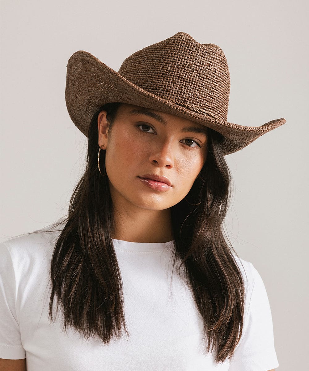 Woman wearing an Ames packable straw cowboy hat, featuring a classic cattleman crown and open-weave design.