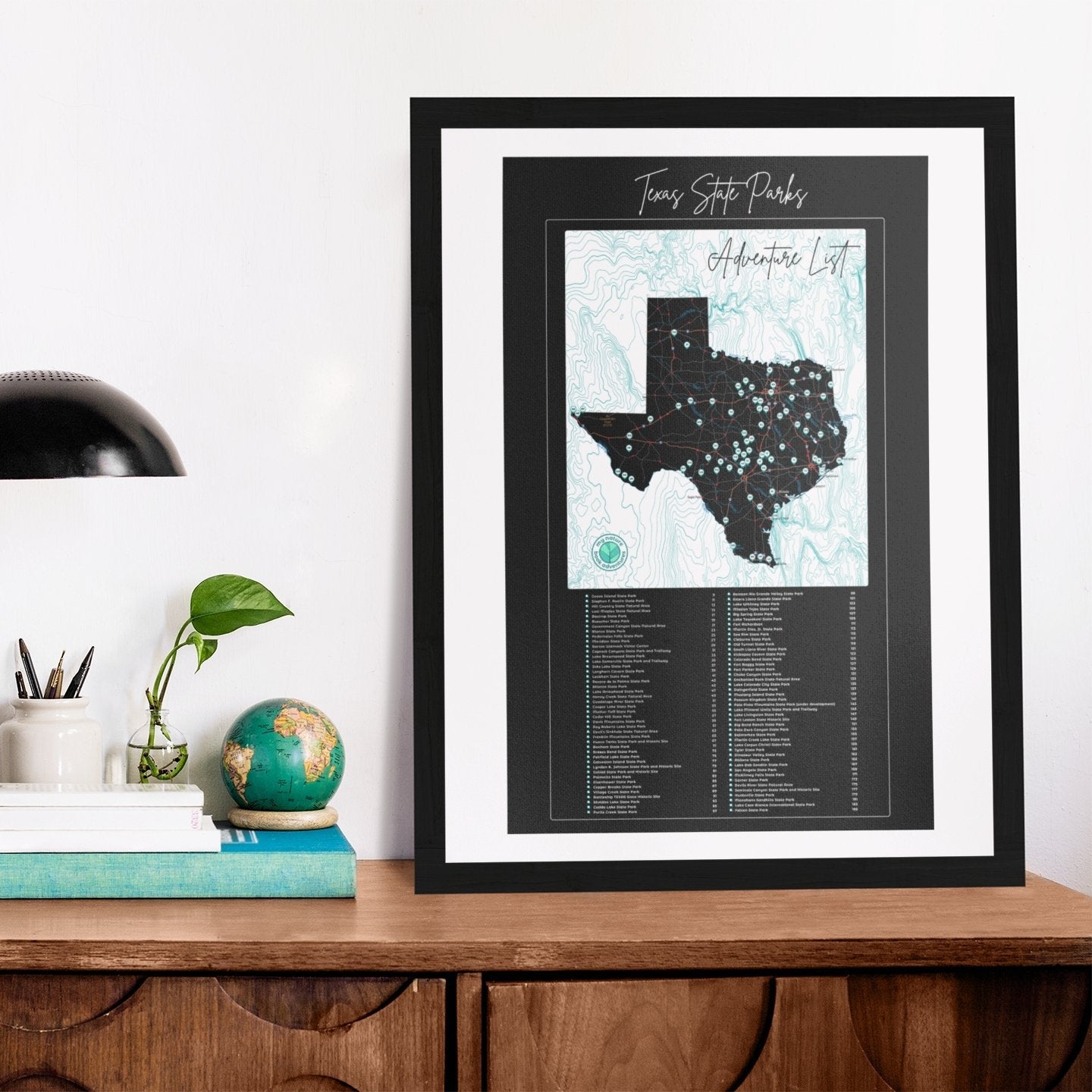 Texas State Parks Adventure List poster displayed on a wooden table, featuring a map of Texas with parks marked.