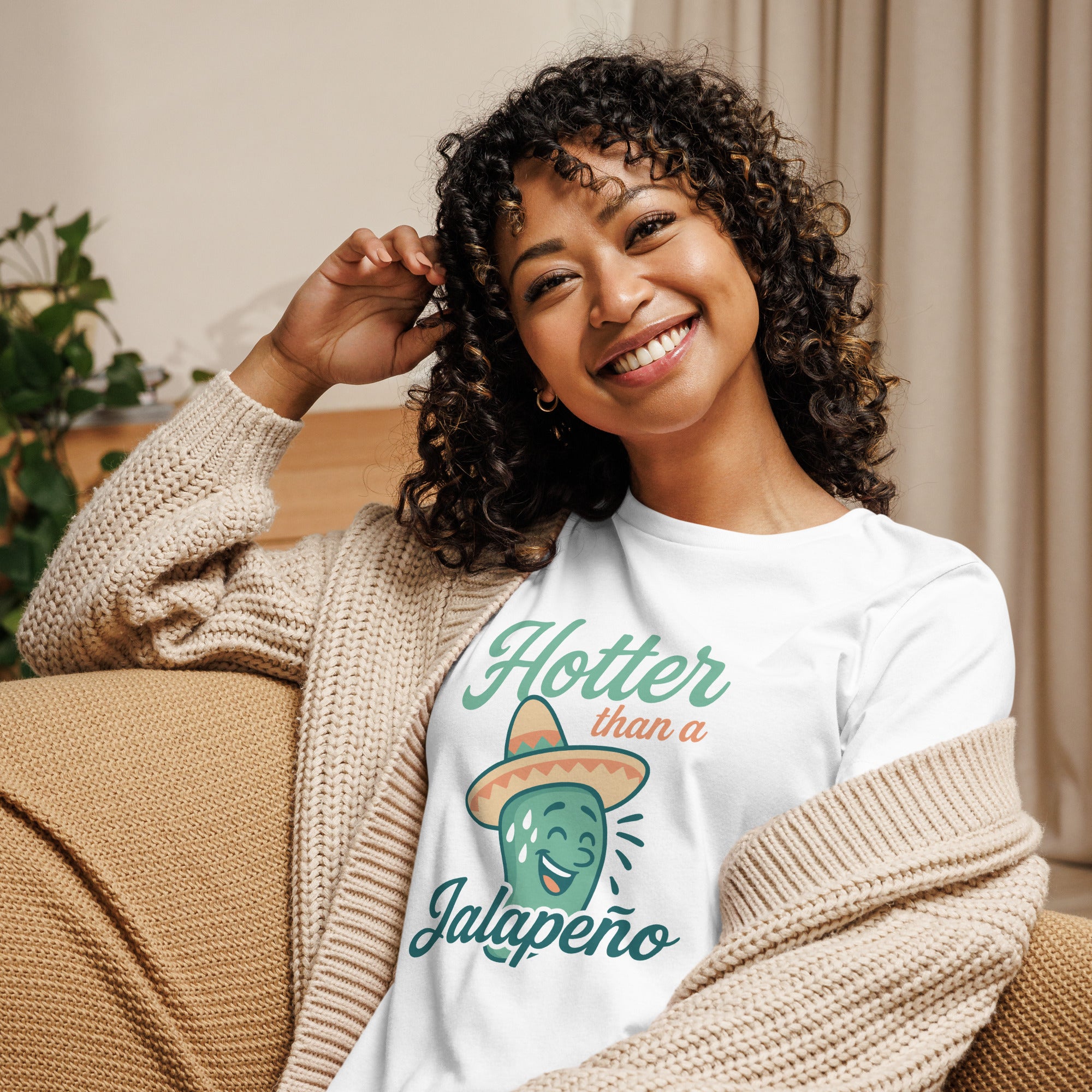 Smiling woman in cozy sweater wearing 'Hotter Than a Jalapeño' graphic tee with a cheerful jalapeño design.